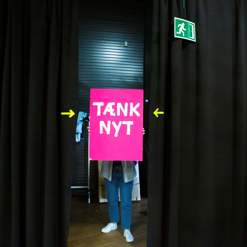 Tænk nyt-skilt ved et scenetæppe