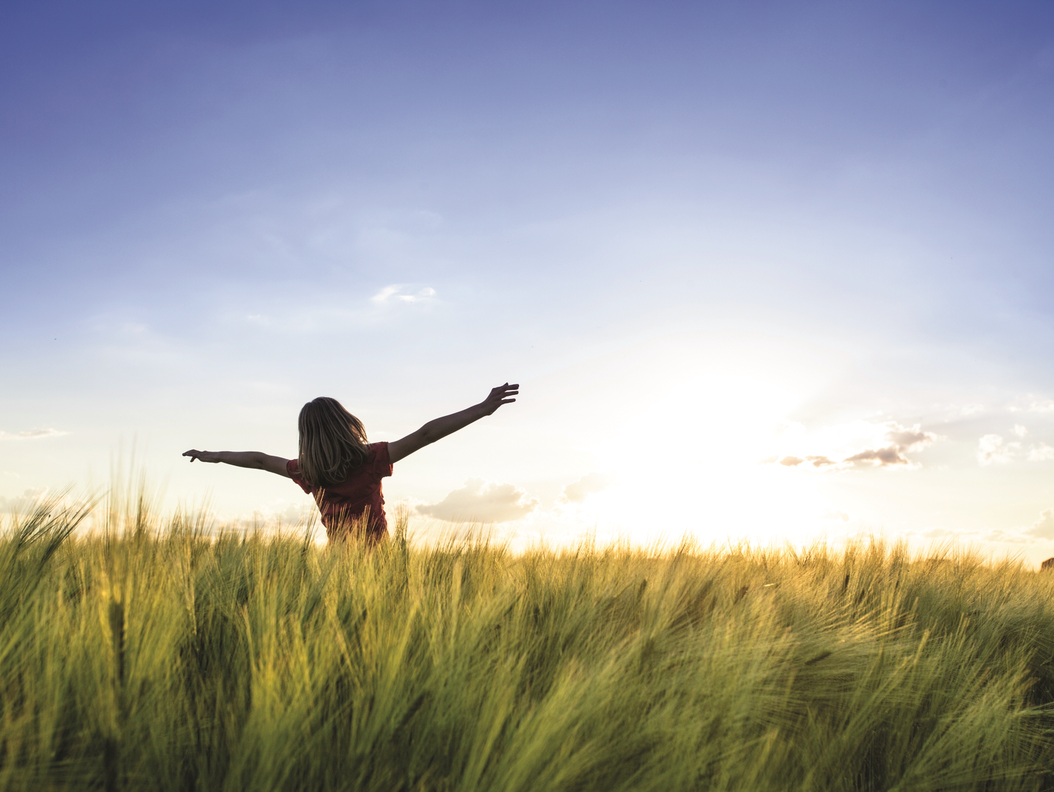 Pige på en mark med armene i vejret