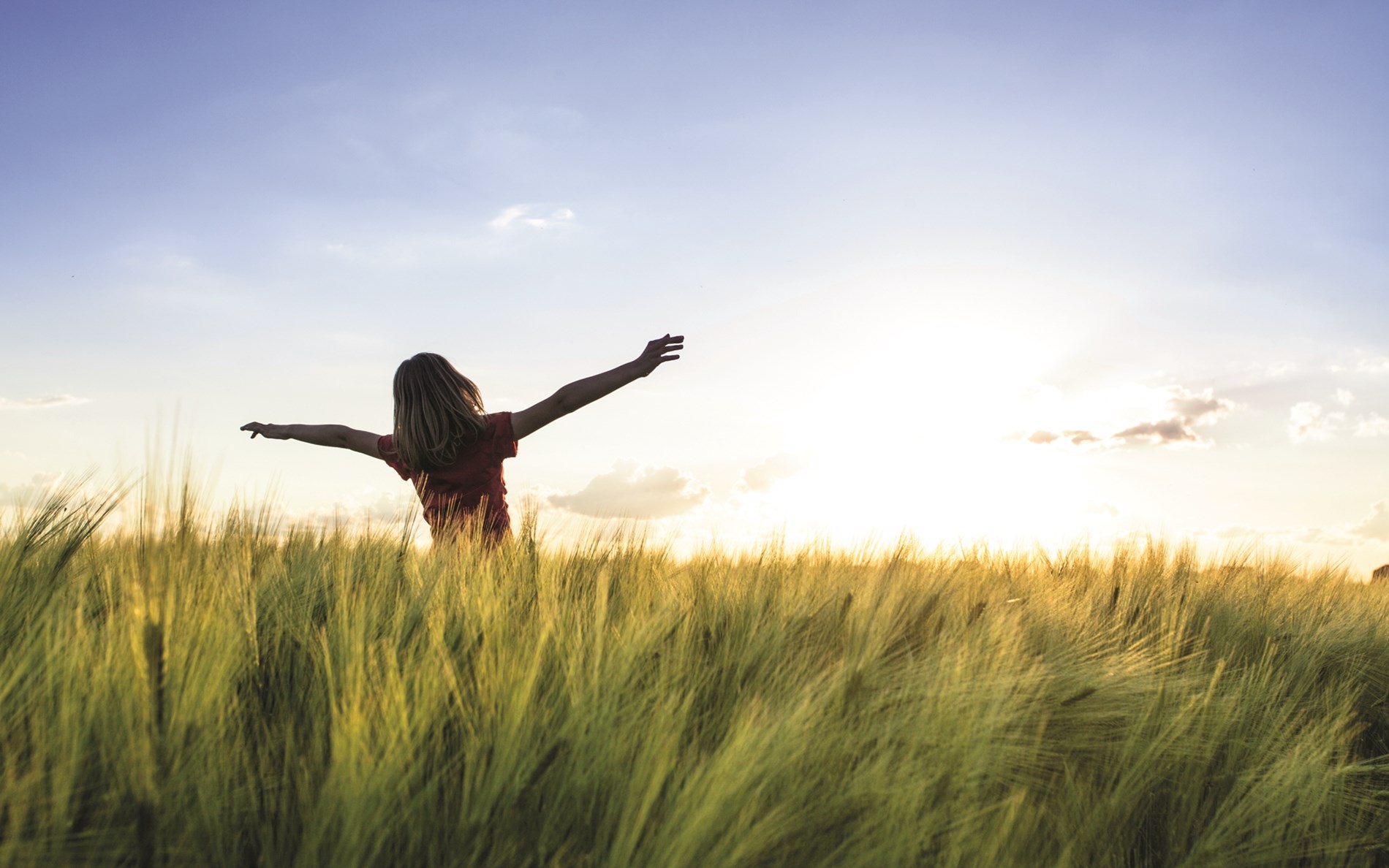 Pige på en mark med armene i vejret