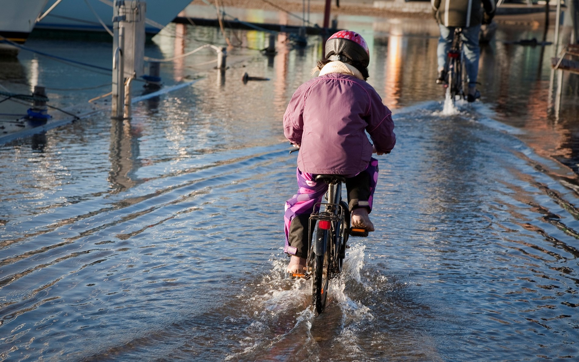 Barn cykler gennem oversvømmet havneområde