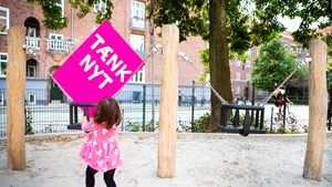 Tænk nyt-skilt bliver gynget af et barn