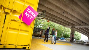 Tænk nyt-skilt ved en gul container, hvor unge mennesker spiller basket